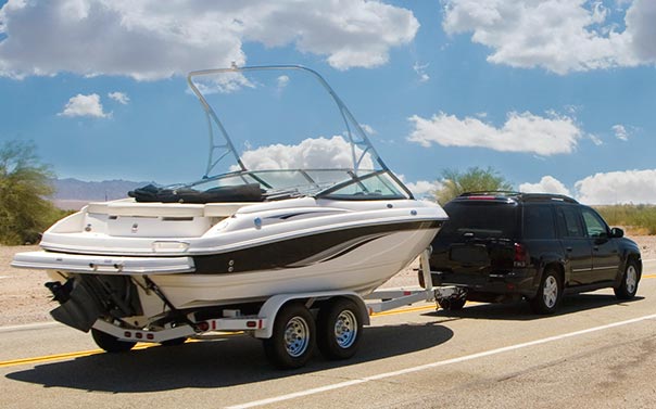 A black SUV pulling a wakeboard boat on a trailer